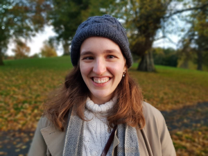 A headshot of a woman wearing a hat in a park